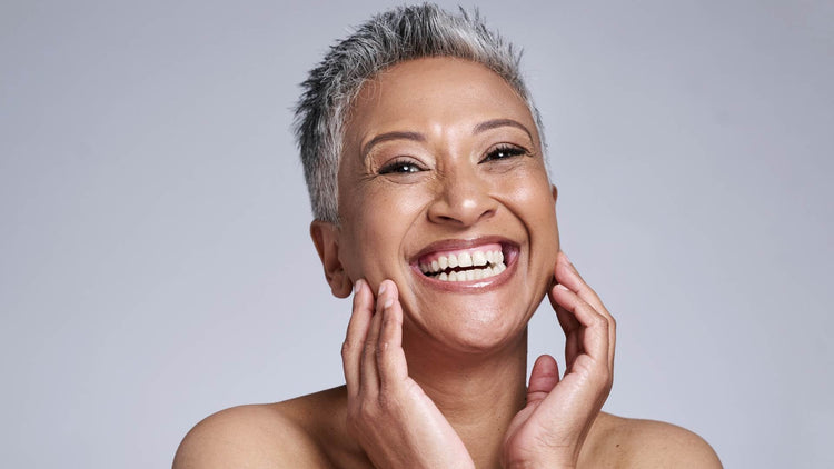 Smiling woman with short grey hair, showcasing radiant skin and joy, representing the benefits of anti-ageing supplements.