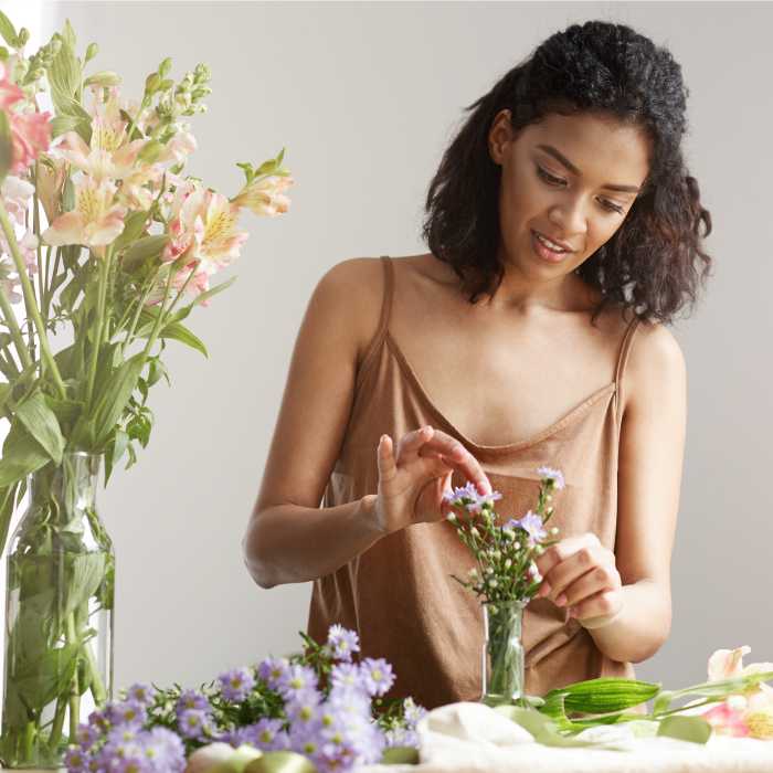 Woman arranging flowers and using essential oils - The Good Stuff.