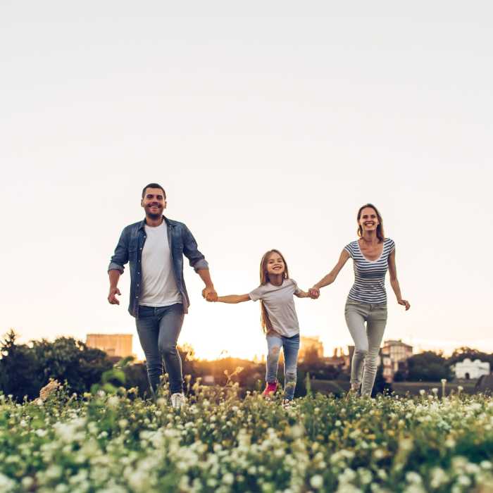 A joyful family of three running through a flower-filled field at sunset, symbolising health, happiness, and vitality, associated with Solgar supplements.