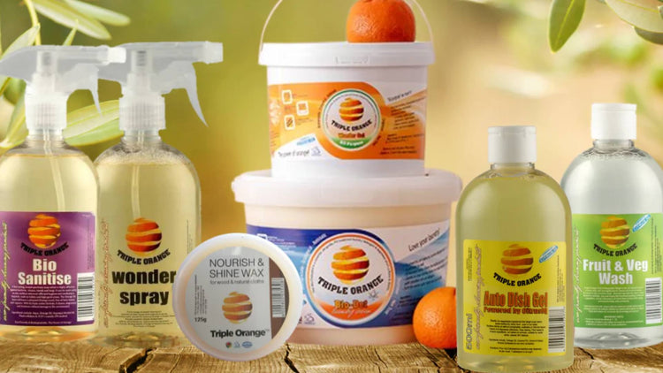 Triple Orange eco-friendly cleaning products, including Bio Sanitise, Wonder Spray, Nourish & Shine Wax, and Auto Dish Gel, on a rustic surface.