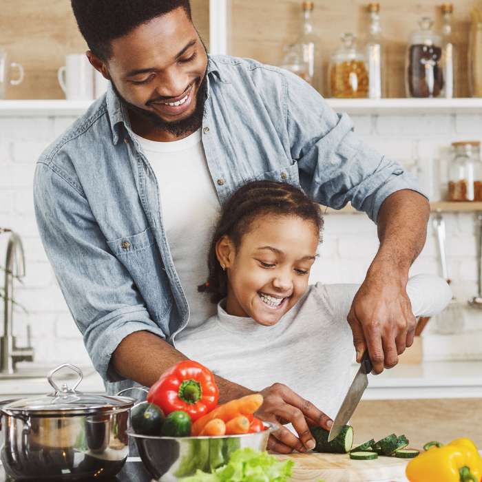 Viridian: Smiling father and daughter preparing vegetables together in a bright kitchen, enjoying family time.