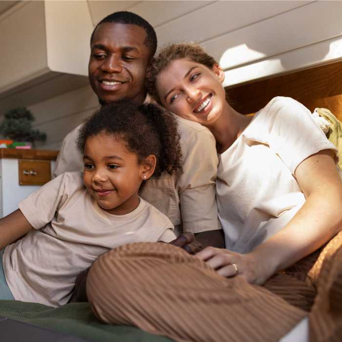 A happy family of three relaxing together at home, representing the wellness and care that Willow supplements from The Good Stuff provide for family health.